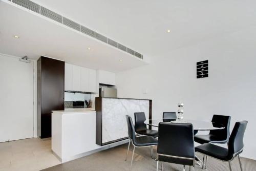 a dining room with a table and black chairs at Realm 12 in Canberra