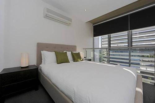 Un dormitorio con una gran cama blanca y una ventana en Mode Apartments Braddon ACT, en Canberra