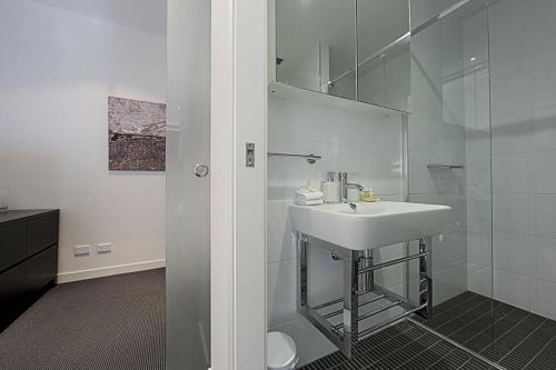 a white bathroom with a sink and a shower at Mode Apartments Braddon ACT in Canberra