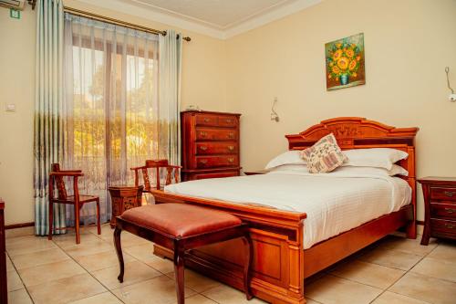 a bedroom with a bed and two chairs and a window at Shangri-la Hotel Muyenga in Bugolobi