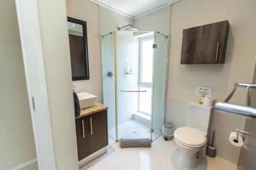 a bathroom with a shower and a toilet and a sink at The Pearls 4th Floor Luxury Apartment with inverter in Summerstrand