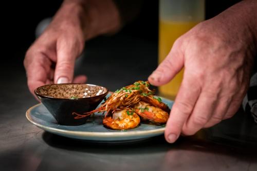 a person holding a plate of shrimp and a sauce at Ruim comfortabel appartement centrum Breda MET restaurant! in Breda