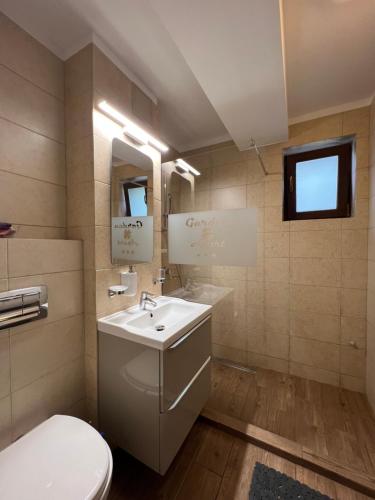 y baño con lavabo blanco y aseo. en Apartamente de inchiriat- Garden Apart Predeal, en Predeal