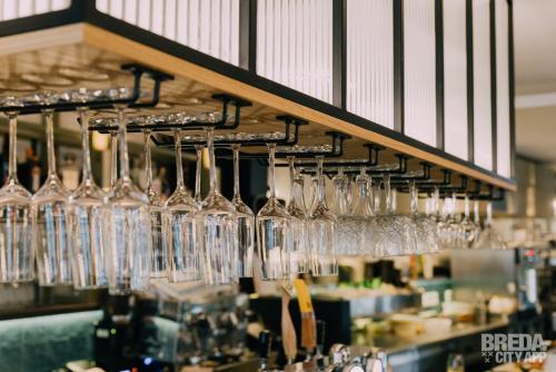 a bunch of wine glasses hanging from a bar at Ruim comfortabel appartement centrum Breda MET restaurant! in Breda