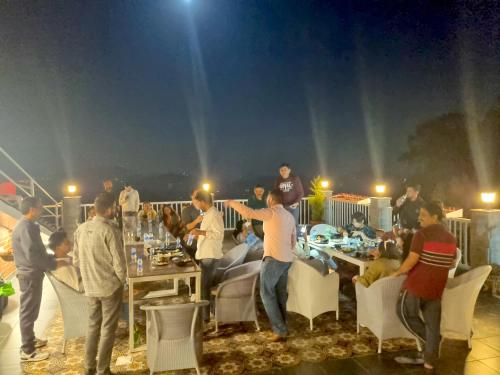 a group of people standing around a table on a rooftop at Hotel Wood Stock Luxury - A Boutique Property - Penthouse - Open Air Restaurant & Terrace in Kasauli