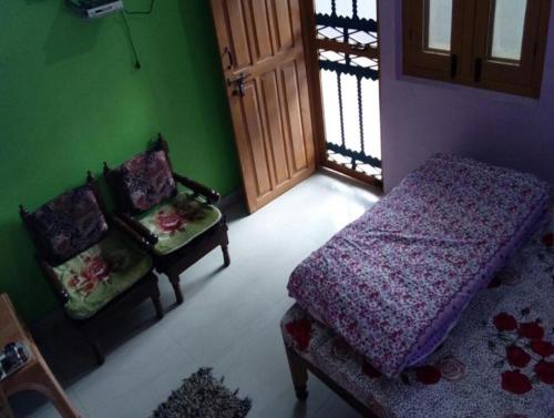 a bedroom with a bed and a chair and a door at StayApart Mount Kailash Guest House in Munsyari