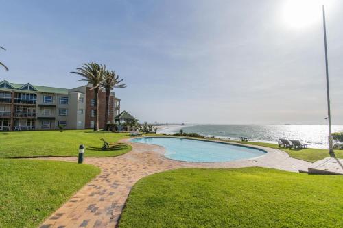 a swimming pool next to a building and the ocean at Brookes Hill Studio, Unit 156 in Port Elizabeth