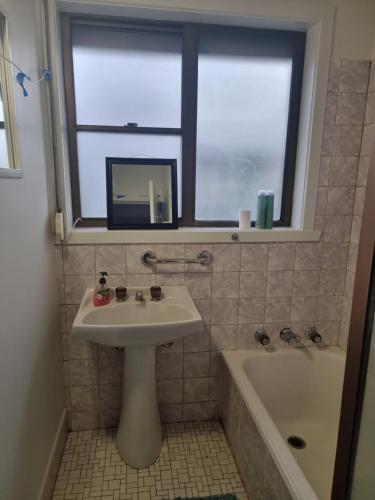 baño con lavabo, ventana y bañera en Two separate rooms in Clayton South, en Clayton North