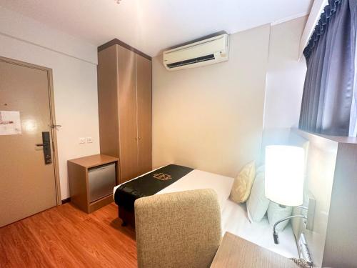 a small room with a bed and a chair at Raia Hotel & Convention Centre Terengganu in Kuala Terengganu