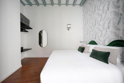 a bedroom with a large white bed with green pillows at Numa Seville Alegre in Seville