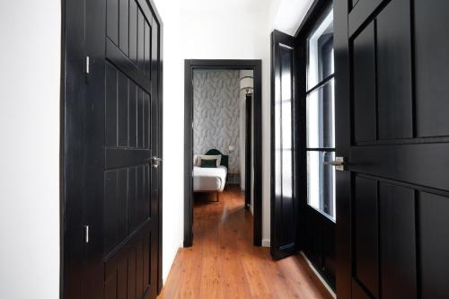 a hallway with two black doors and a bedroom at Numa Seville Alegre in Seville