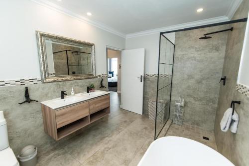 y baño con lavabo y ducha con espejo. en Tivoli Luxury Beach Apartment en Port Elizabeth