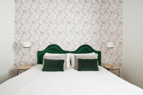 a bedroom with a white bed with two green pillows at Numa Seville Alegre in Seville