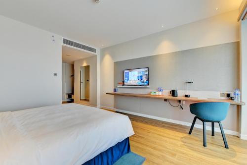 a hotel room with a bed and a desk and a tv at Holiday Inn Express Xiamen Airport Zone by IHG in Xiamen