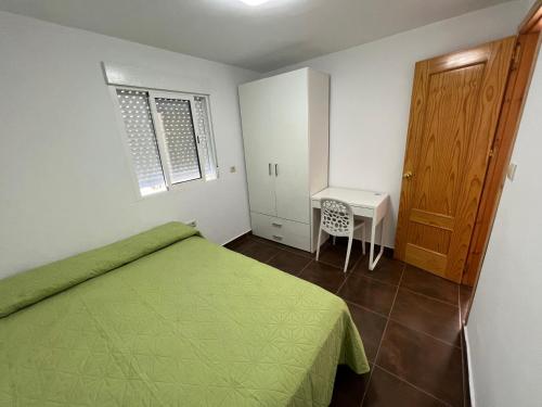 a bedroom with a green bed and a small table at Casa Elsa Ceuta in Ceuta