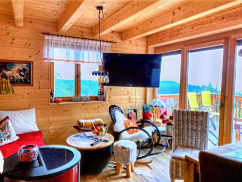 a living room with wooden walls and furniture and windows at Chalet in Bad Leonhard near Klippitztörl Slopes in Klippitztorl