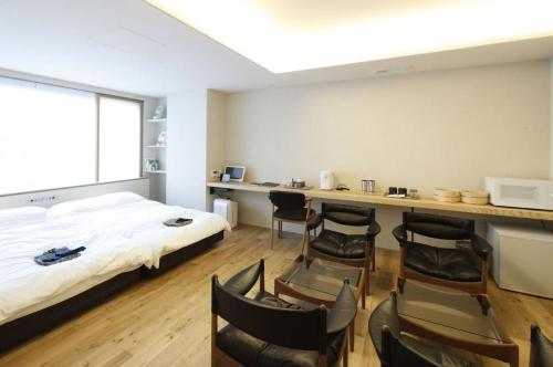 a room with a bed and a desk and chairs at Matsumoto Jujo in Matsumoto