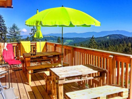 a patio with tables and an umbrella on a deck at Chalet in Bad Leonhard near Klippitztörl Slopes in Klippitztorl