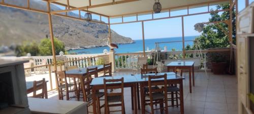 a restaurant with tables and chairs and a view of the ocean at Alkyonis Apartments in Panormos Kalymnos