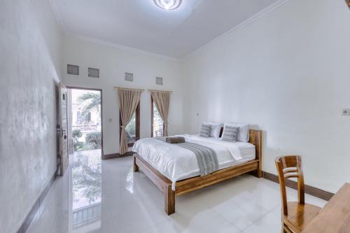 Dormitorio blanco con cama y ventana grande en Yuda Homestay en Nusa Penida
