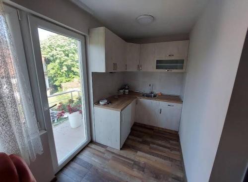 a kitchen with white cabinets and a large window at Seosko domacinstvo Nedic in Valjevo