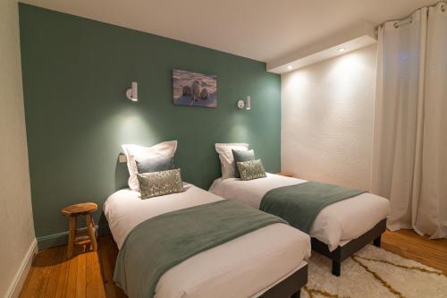 deux lits dans une chambre aux murs verts dans l'établissement Bleu des Vosges, à Gérardmer