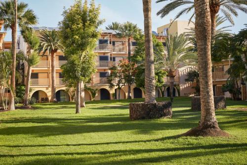 an apartment building with palm trees in a park at ROBINSON JANDIA PLAYA - Adults only in Morro del Jable