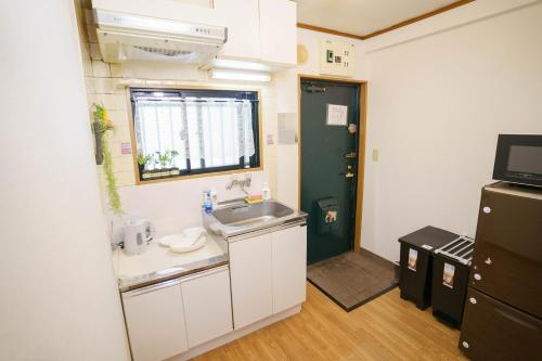 uma pequena cozinha com um lavatório e uma janela em BURan House em Tóquio
