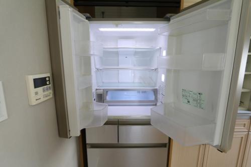 an empty refrigerator with its door open in a kitchen at ELLE Namba Villa in Osaka