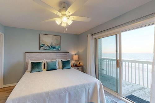 um quarto com uma cama, uma ventoinha de tecto e uma varanda em Sand Castle em Kure Beach