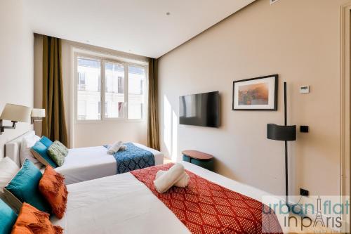 une chambre d'hôtel avec deux lits et une fenêtre dans l'établissement 141 - Beautiful Flat Triangle d Or Champs Elysees, à Paris