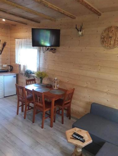 a dining room with a table and a tv on a wall at Rajskie wzgórze w Karkonoszach in Łomnica
