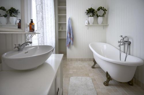 a white bathroom with a tub and a sink at Pensionat Kajutan I Sjötorp in Sjötorp