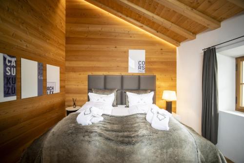 - une chambre avec un grand lit et des murs en bois dans l'établissement Chasa Sömmi, à Ftan