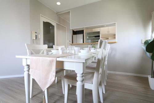 a white dining room with a white table and chairs at ELLE Namba Villa in Osaka
