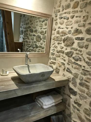 Baño de piedra con lavabo y espejo en Chambre LA LONGERE, en Treffort