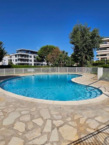 une grande piscine avec de l'eau bleue dans une cour dans l'établissement Studio Saint-Laurent-Du-Var bord de mer, à Saint-Laurent-du-Var