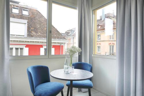 a table and chairs in a room with a window at numa I Turi Apartments in Zürich