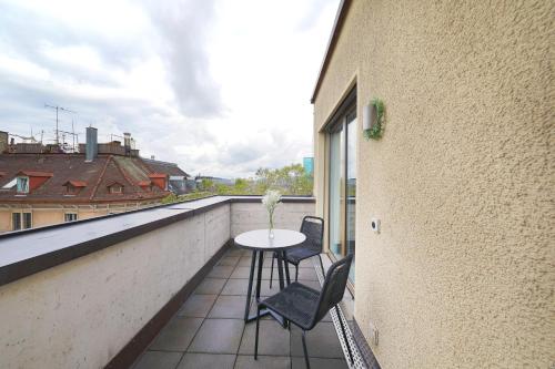 einen Balkon mit einem Tisch und 2 Stühlen auf einem Gebäude in der Unterkunft numa I Turi Apartments in Zürich