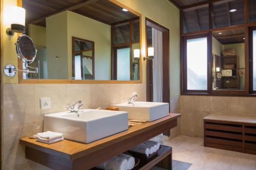 a bathroom with two sinks and a mirror at Komaneka at Tanggayuda Ubud in Ubud