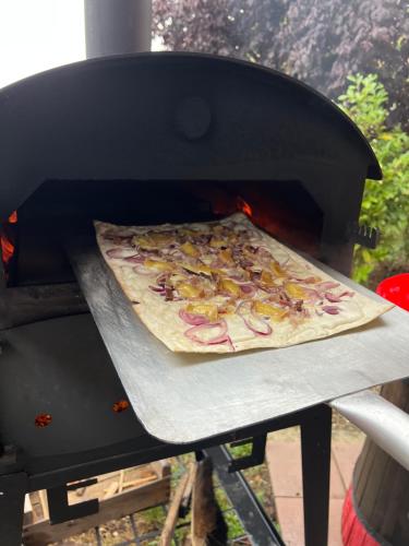 a pizza is being cooked in a grill at L'éclos des vignes - Appartements haut de gamme avec Spa in Bergheim