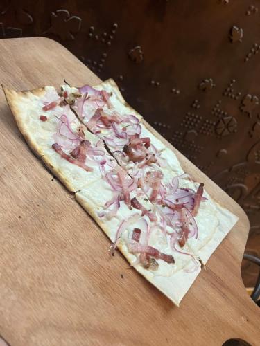 a pizza with onions on it sitting on a table at L'éclos des vignes - Appartements haut de gamme avec Spa in Bergheim