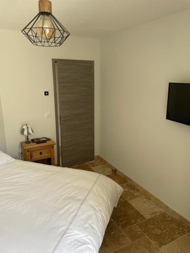 um quarto com uma cama branca e uma televisão em Chambre d hôtes LA MANDALA em Plan dʼAups
