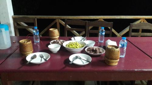 una mesa con tazones de comida y botellas de agua en Ban Na Pia - Family Home stay en Muang Phônsavan