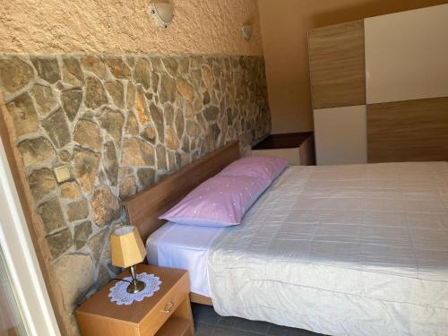 a bedroom with a bed and a stone wall at Kuća za odmor Ivančica in Tisno