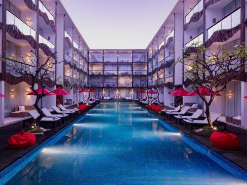 a large swimming pool in a building with chairs at The Bene Hotel in Kuta