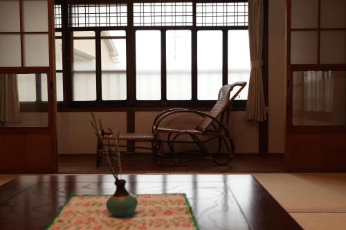 a room with a chair and a vase on a table at つばめ荘 Tsubamesou 尾道駅から徒歩と渡船で15分 情緒あふれる尾道ステイ 鍵付き駐輪場と駐車場あり supported by COCOSTAY in Onomichi