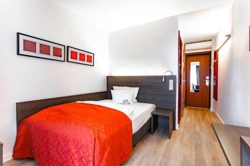 a bedroom with a bed with an orange blanket at Art & Business Hotel in Nürnberg