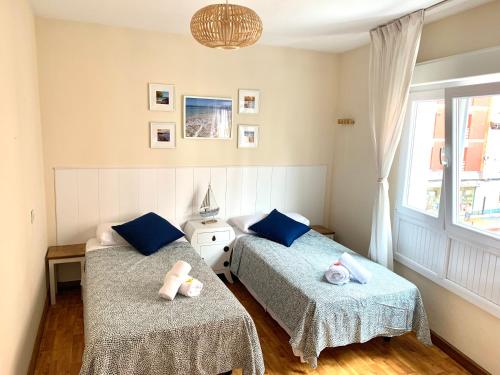 a bedroom with two beds with blue pillows and a window at Sofia´s Canto del Mar in Candás