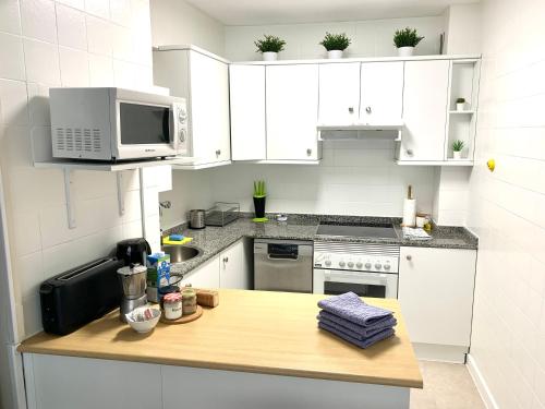 a kitchen with white cabinets and a counter with a microwave at Sofia´s Canto del Mar in Candás